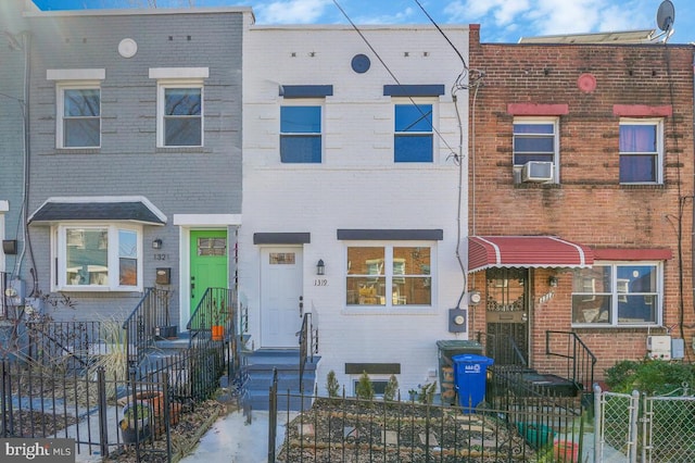 view of property featuring a fenced front yard, cooling unit, and brick siding