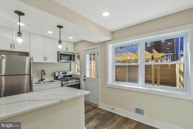 kitchen with visible vents, white cabinetry, appliances with stainless steel finishes, light stone countertops, and decorative light fixtures