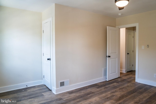 unfurnished room featuring baseboards, visible vents, and dark wood-type flooring