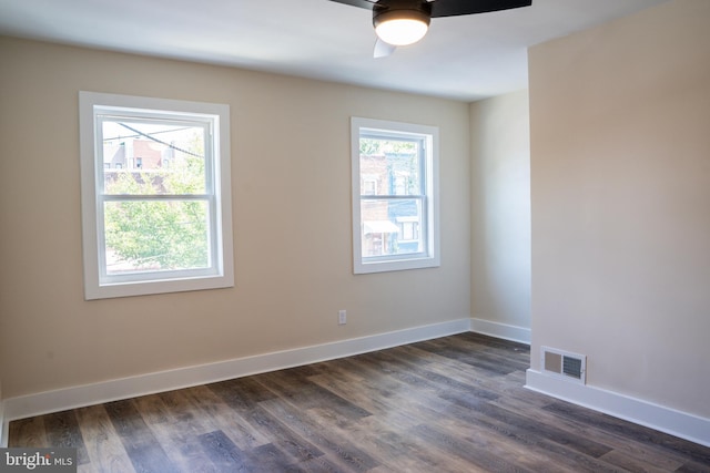 spare room with baseboards, visible vents, dark wood finished floors, and a ceiling fan