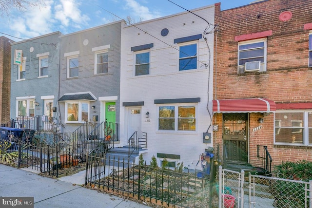 view of property with brick siding, a fenced front yard, and cooling unit