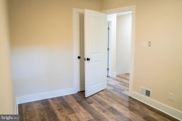 unfurnished room with baseboards, visible vents, and dark wood-type flooring