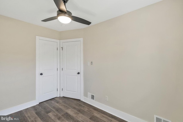 unfurnished bedroom featuring a ceiling fan, dark wood-style flooring, visible vents, and baseboards