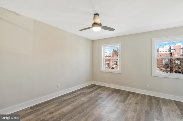 unfurnished room featuring baseboards, a wealth of natural light, and wood finished floors