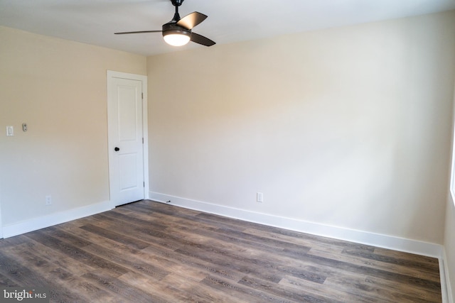 spare room featuring dark wood-style flooring, a ceiling fan, and baseboards