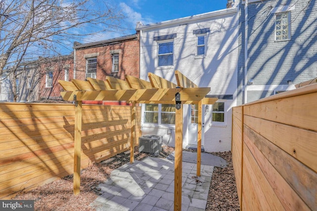 exterior space featuring a patio, fence private yard, central air condition unit, a pergola, and brick siding