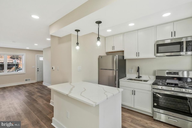 kitchen with appliances with stainless steel finishes, a sink, light stone countertops, and white cabinets