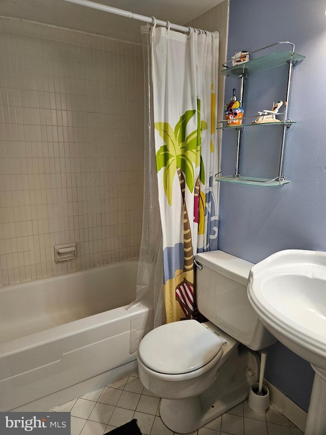 full bath with shower / tub combo with curtain, a sink, toilet, and tile patterned floors