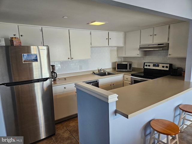 kitchen featuring stainless steel appliances, white cabinetry, a peninsula, under cabinet range hood, and a kitchen bar