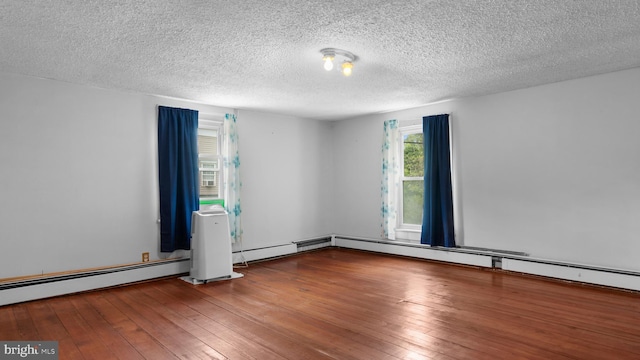 empty room with hardwood / wood-style flooring, a baseboard radiator, and a textured ceiling