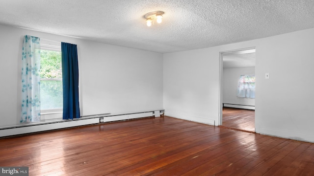 empty room with dark hardwood / wood-style floors, a textured ceiling, and baseboard heating