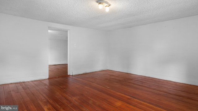 empty room with dark hardwood / wood-style flooring and a textured ceiling