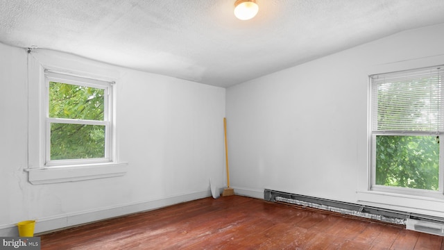 empty room with hardwood / wood-style flooring, a baseboard radiator, and vaulted ceiling