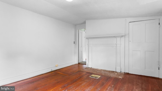 unfurnished bedroom with lofted ceiling, dark hardwood / wood-style floors, a textured ceiling, and a closet