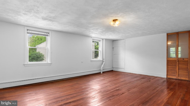 spare room featuring a baseboard heating unit, dark hardwood / wood-style floors, and a textured ceiling