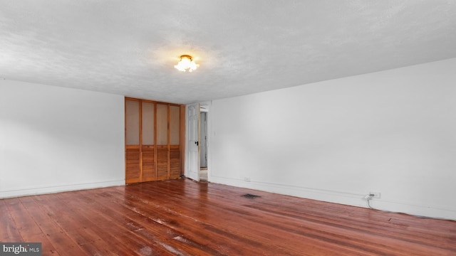 spare room with dark hardwood / wood-style floors and a textured ceiling