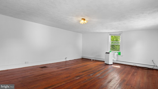 empty room with a baseboard radiator, dark hardwood / wood-style floors, and a textured ceiling