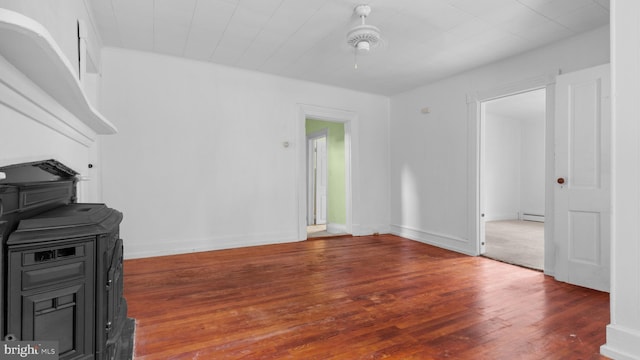 unfurnished living room with a baseboard heating unit and dark hardwood / wood-style floors