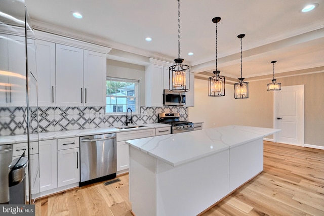 kitchen with white cabinets, sink, decorative light fixtures, a kitchen island, and stainless steel appliances