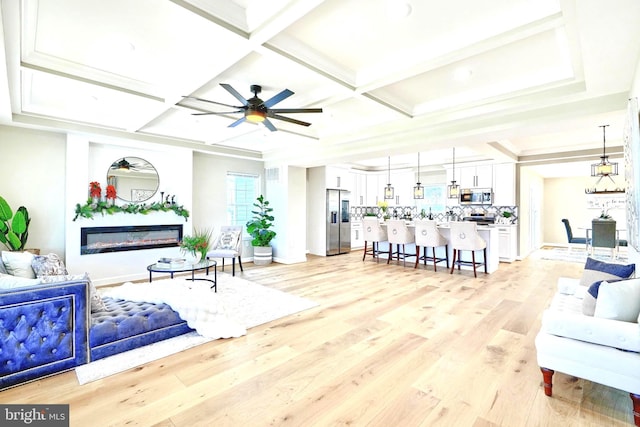 living room featuring ceiling fan, coffered ceiling, beam ceiling, and light hardwood / wood-style flooring