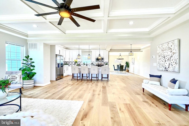 living room featuring coffered ceiling, crown molding, light hardwood / wood-style flooring, and beamed ceiling