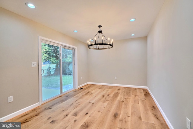 unfurnished dining area featuring an inviting chandelier and light hardwood / wood-style flooring