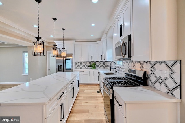 kitchen with appliances with stainless steel finishes, a kitchen island, sink, white cabinetry, and hanging light fixtures