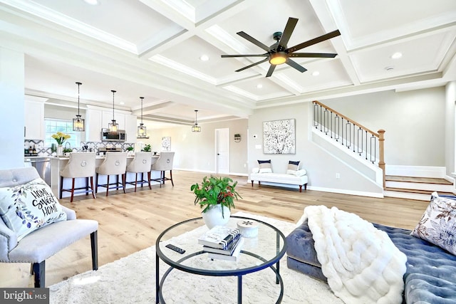 living room featuring coffered ceiling, light hardwood / wood-style flooring, ornamental molding, and beamed ceiling