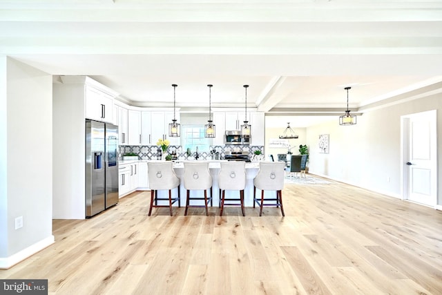 kitchen with light stone counters, ceiling fan with notable chandelier, light hardwood / wood-style floors, white cabinetry, and hanging light fixtures