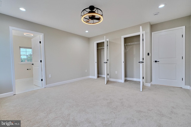 unfurnished bedroom with light colored carpet and two closets