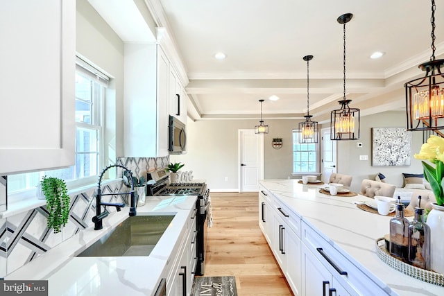 kitchen featuring stainless steel appliances, light stone countertops, hanging light fixtures, and white cabinets