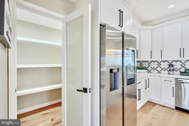 kitchen featuring white cabinetry, decorative backsplash, light hardwood / wood-style floors, and appliances with stainless steel finishes