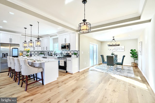 kitchen with pendant lighting, stainless steel appliances, a kitchen island, and white cabinets