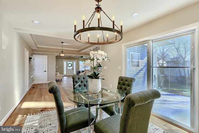 dining room with ornamental molding, a tray ceiling, a chandelier, and light hardwood / wood-style floors