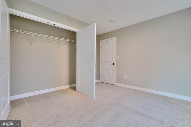 unfurnished bedroom with light carpet and a closet