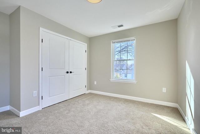 unfurnished bedroom with light carpet and a closet