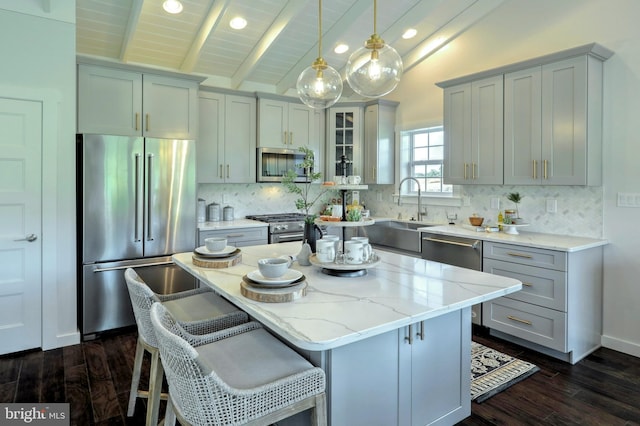 kitchen featuring vaulted ceiling with beams, stainless steel appliances, backsplash, a kitchen island, and dark wood-type flooring