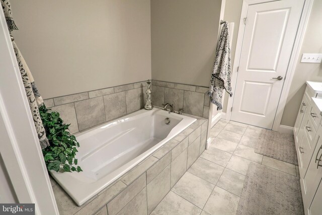 bathroom with tiled tub, tile patterned floors, and vanity