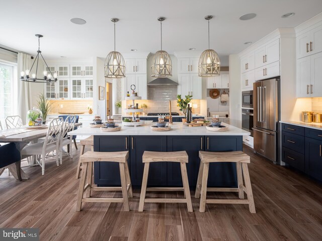 kitchen featuring hanging light fixtures, a kitchen breakfast bar, a kitchen island, stainless steel appliances, and white cabinets