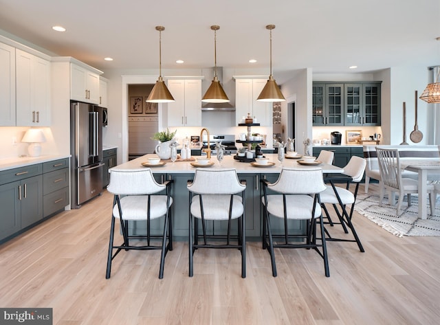 kitchen with gray cabinets, appliances with stainless steel finishes, pendant lighting, white cabinets, and a kitchen island with sink