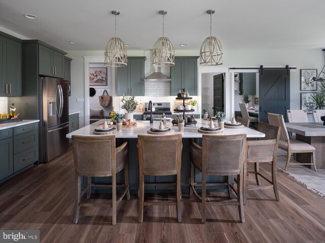 kitchen with pendant lighting, dark hardwood / wood-style floors, stainless steel appliances, and a barn door