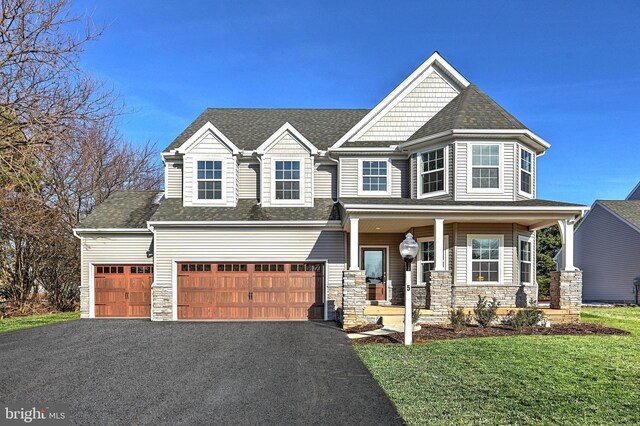 view of front of house with a garage, a front lawn, and covered porch