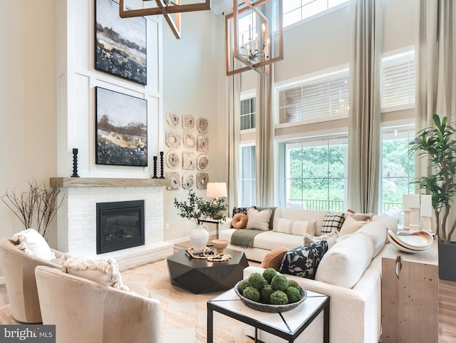 living room with an inviting chandelier, a towering ceiling, and a fireplace