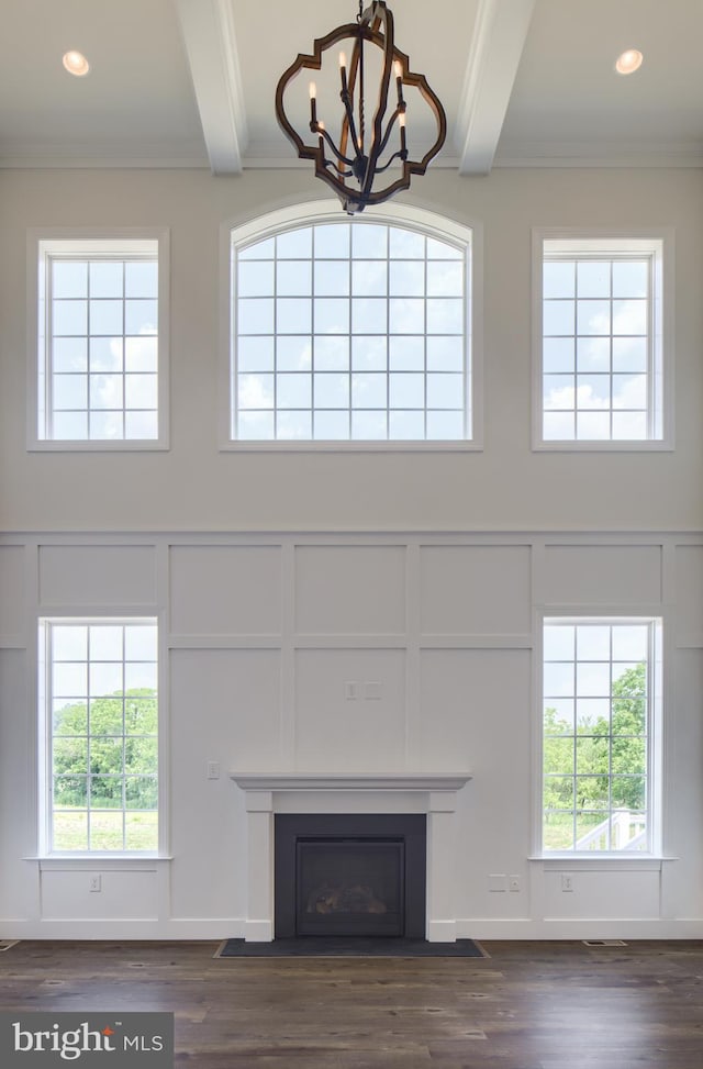 unfurnished living room featuring crown molding, dark hardwood / wood-style floors, beam ceiling, and a chandelier