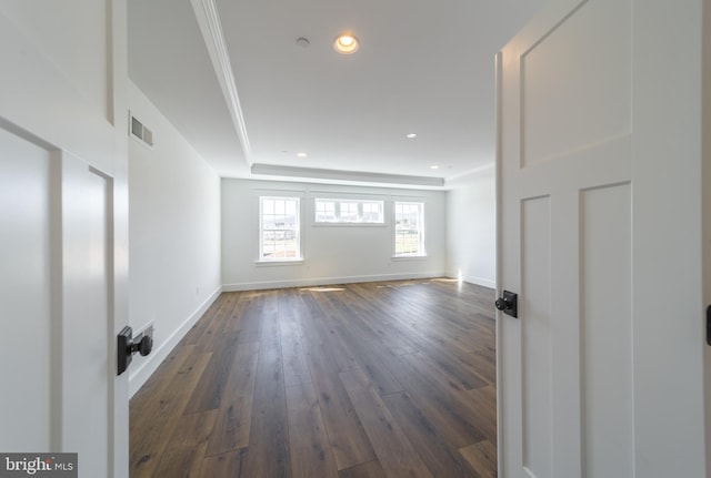 spare room with dark wood-type flooring and a tray ceiling