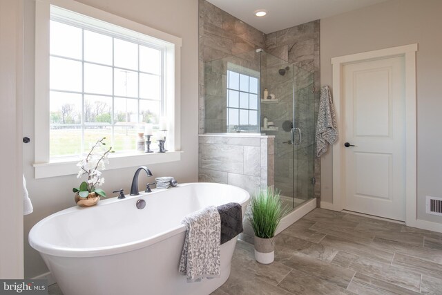 bathroom with a stall shower, visible vents, and a freestanding bath