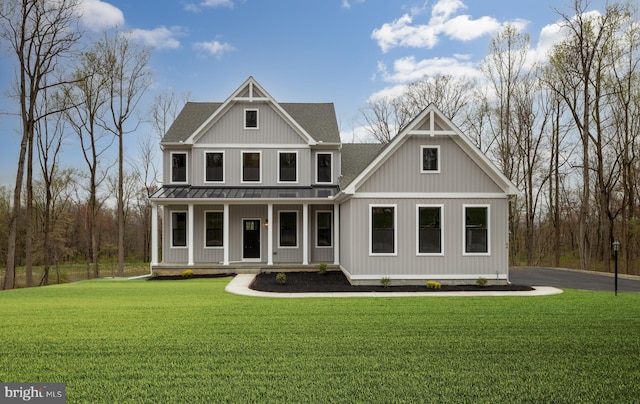 view of front of home with a shingled roof, a porch, metal roof, a standing seam roof, and a front lawn