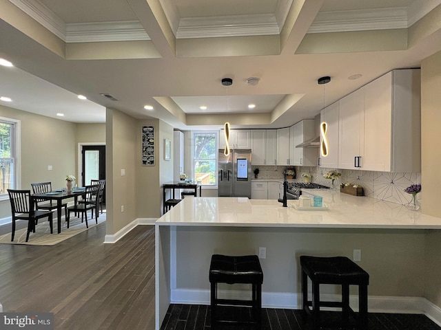 kitchen featuring a healthy amount of sunlight, stainless steel fridge, dark wood-type flooring, and kitchen peninsula