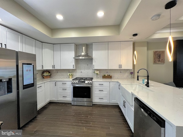 kitchen featuring stainless steel appliances, pendant lighting, kitchen peninsula, and wall chimney exhaust hood