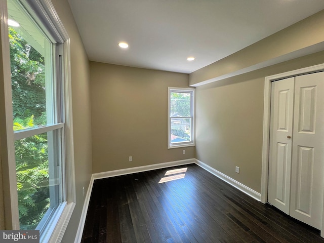 unfurnished bedroom with dark hardwood / wood-style flooring and a closet